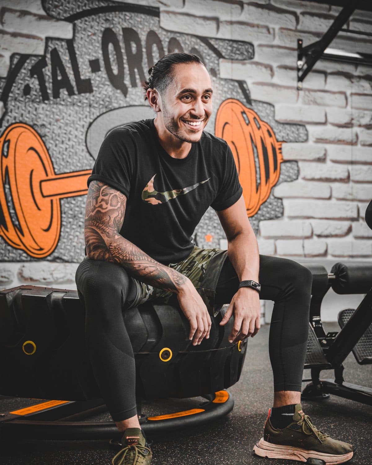 Coach Mark, sitting on a tyre in the gym, smiling